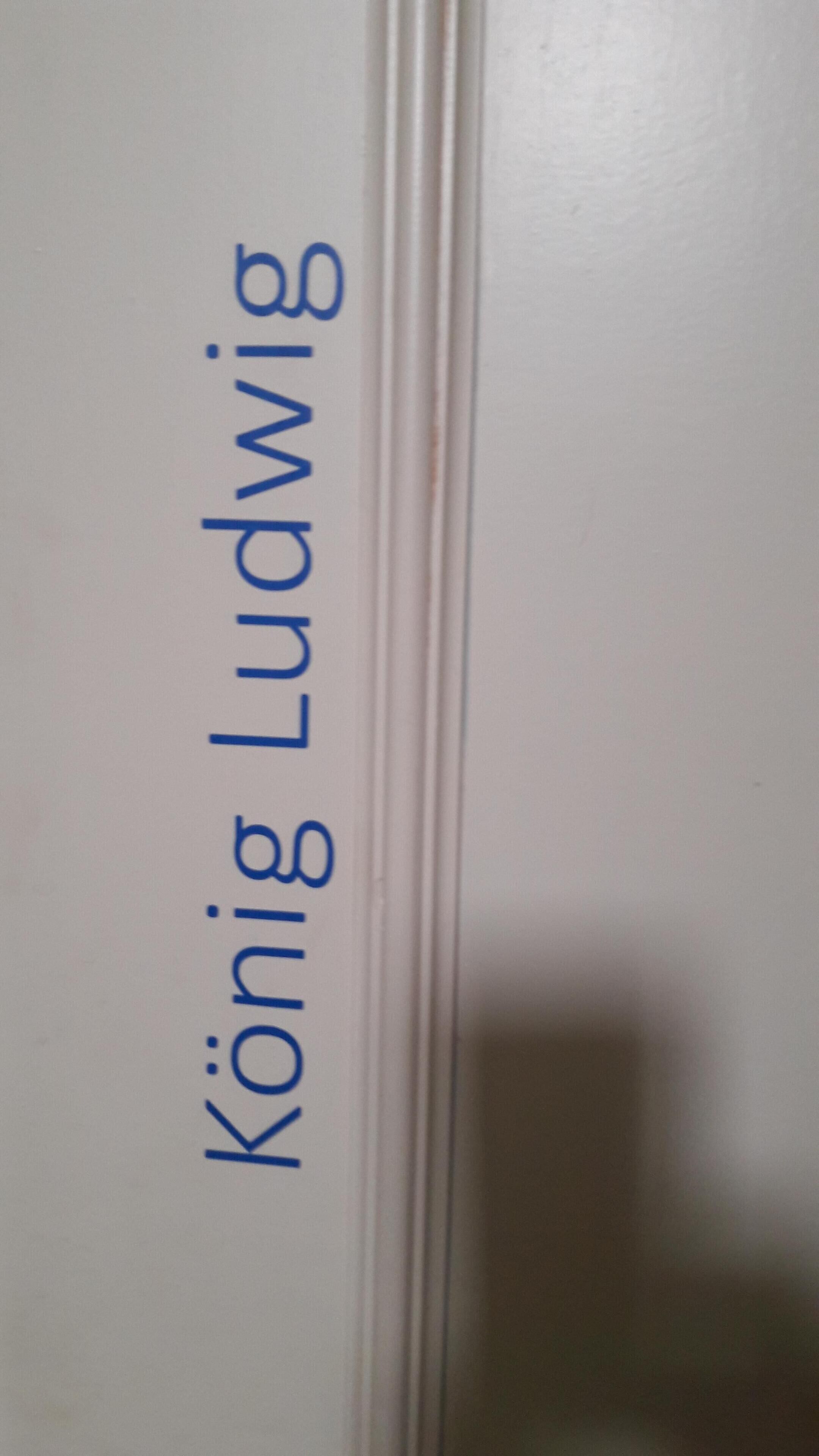 Een witte deur met de naam 'König Ludwig' in blauwe letters.