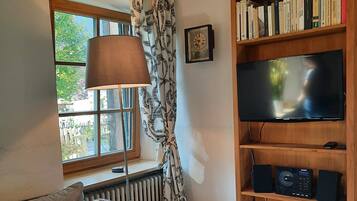 A cozy living room with a sofa, a lamp, a bookshelf, and a TV.