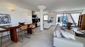 A modern kitchen with a bar area, a dining set, and a large window overlooking a pool. - Villa Bianca, with its own pool and Wi-Fi, close to the ocean, sheltered courtyard (patio) (Costa Calma)