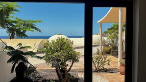 A view through a doorway of a building with a beach and palm trees in the background. - Villa Bianca, with its own pool and Wi-Fi, close to the ocean, sheltered courtyard (patio) (Costa Calma)