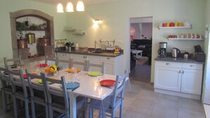 A dining area with a table set for four, a kitchen with white cabinets, and a living area with a sofa and coffee machine. - Character house for 12 people, PRIVATE POOL (Lussas)