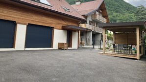Ein modernes Gebäude mit geneigtem Dach, großen Garagentoren und einem überdachten Außenbereich zum Sitzen.