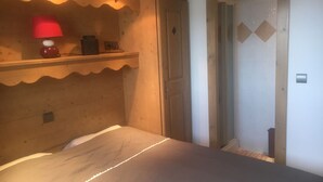 A bedroom with a bed, a red lamp on a shelf, and a door with a diamond pattern. - Arc 1800 Iseran, ski-in ski-out, heated swimming pool, cleaning included (Bourg-Saint-Maurice)