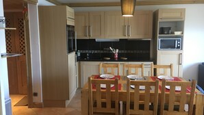 A kitchen with wooden cabinets, a black countertop, a microwave, and a dining table with chairs. - Arc 1800 Iseran, ski-in ski-out, heated swimming pool, cleaning included (Bourg-Saint-Maurice)