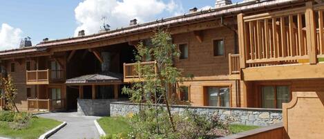 A multi-story wooden building with balconies, a stone foundation, and a clear sky.