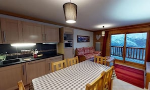 Enjoy meals in this kitchen with a dining table for four, a large window offering a scenic view, and a hanging light fixture.