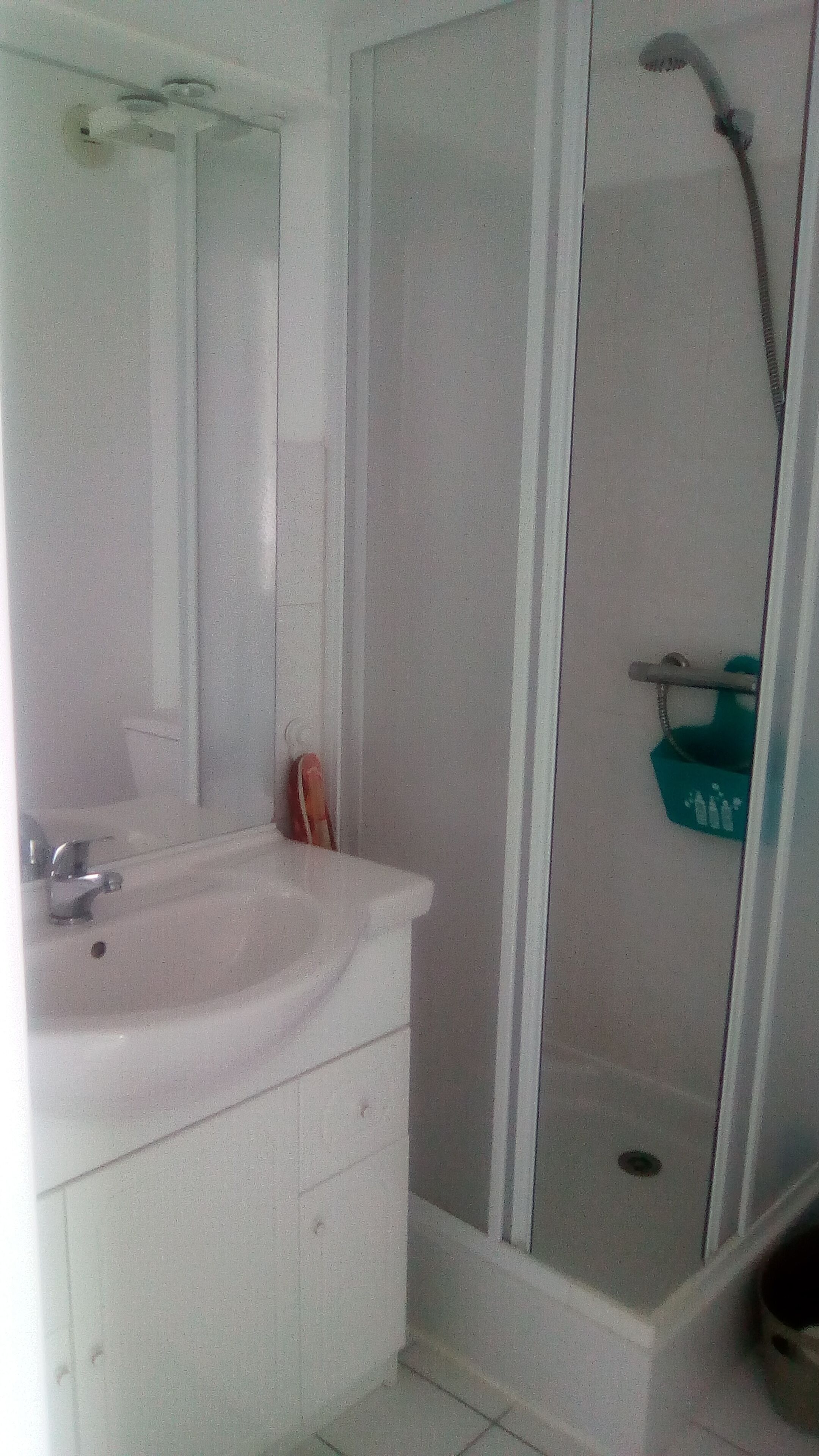 Casa de banho com lavatório branco, espelho e cabine de duche.