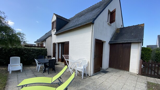 A house with a patio area featuring a table and chairs, a small garden, and a wooden gate. - CLOS DUNES - Jardin, Piscine partagée - ED6019 (Erdeven)