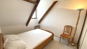 A small, single-bed room with sloped wooden beams, a radiator, and a wooden chair. - CLOS DUNES - Jardin, Piscine partagée - ED6019 (Erdeven)