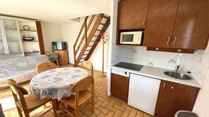 A compact kitchen with a wooden table, chairs, a microwave, a dishwasher, and a small sink. - CLOS DUNES - Jardin, Piscine partagée - ED6019 (Erdeven)
