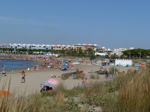 Een druk strand met mensen die zonnebaden en zwemmen.