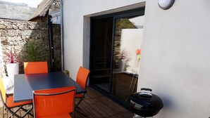 Una terrazza esterna con tavolo e sedie, un barbecue e un muro in pietra.