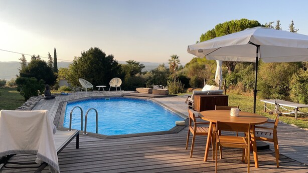 Une terrasse en bois avec une piscine, du mobilier d’extérieur et une vue sur le paysage.
