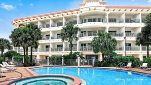 Un hôtel doté d’une piscine, de plusieurs balcons et de palmiers.