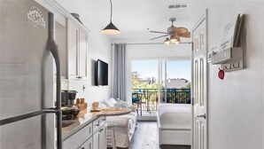 Une cuisine compacte équipée d’un réfrigérateur, un coin repas avec une table et des chaises, un lit et un balcon avec vue.