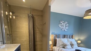 Un dormitorio moderno con piso de madera, una cama grande con ropa de cama a rayas, una mesita de noche y una decoración de peces colgada en la pared.