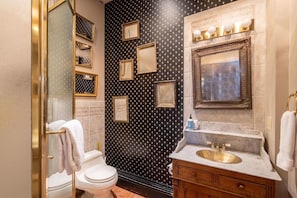 Une salle de bain comprenant des toilettes, un meuble-lavabo avec un évier et un grand miroir.