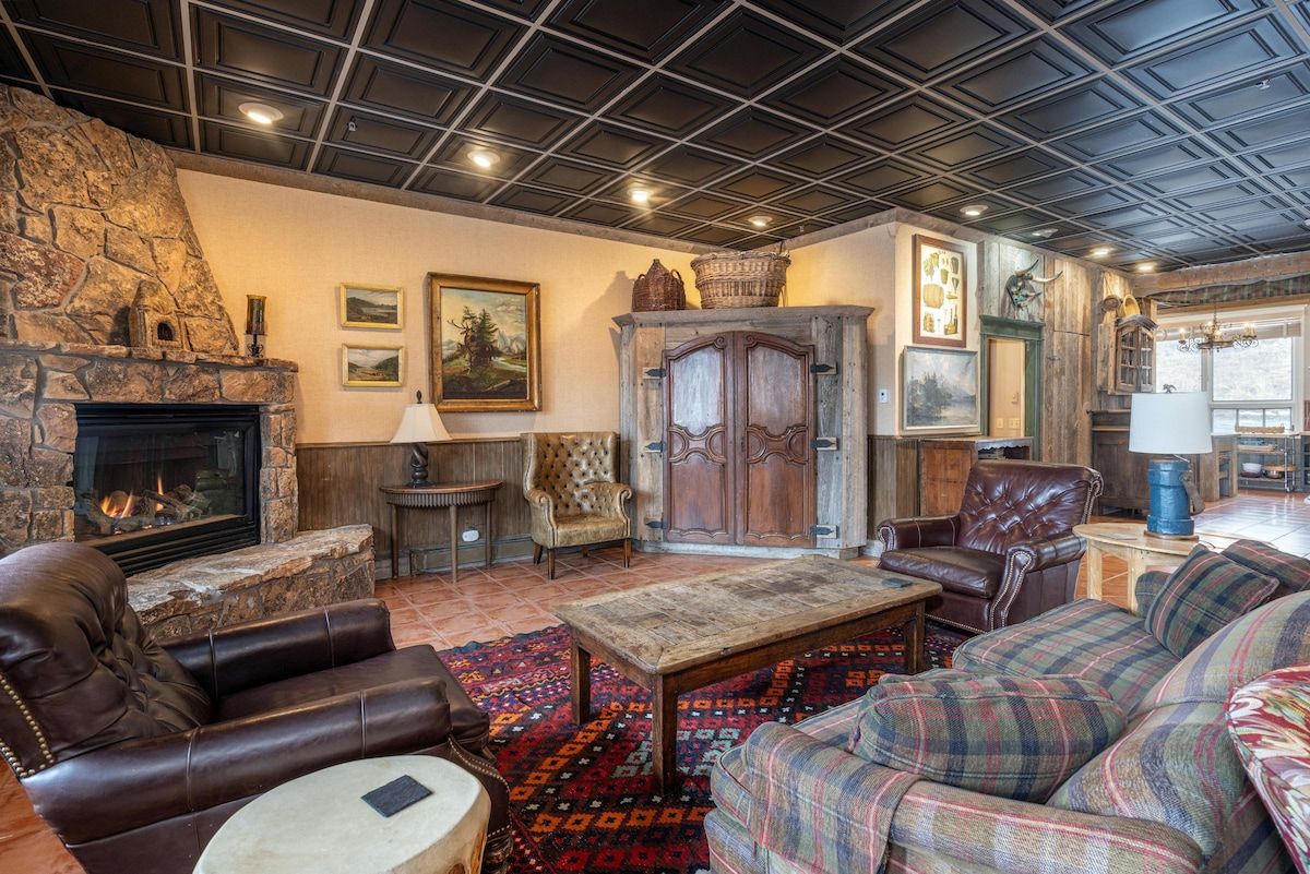 Una sala de estar acogedora con chimenea de piedra, muebles de cuero y una alfombra estampada.
