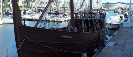 A wooden boat docked at a marina with other boats in the background.