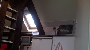 Een kleine keuken met dakraam, een witte koelkast en een houten vloer.