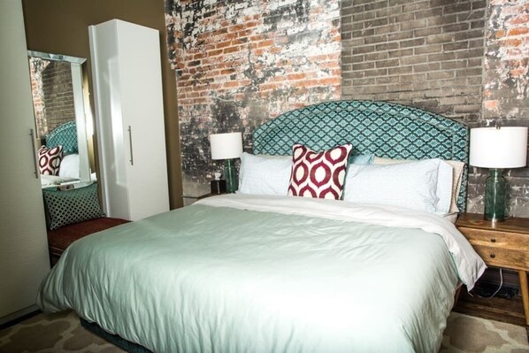 A bed with a patterned headboard, two bedside lamps, and a mirror above the bed.