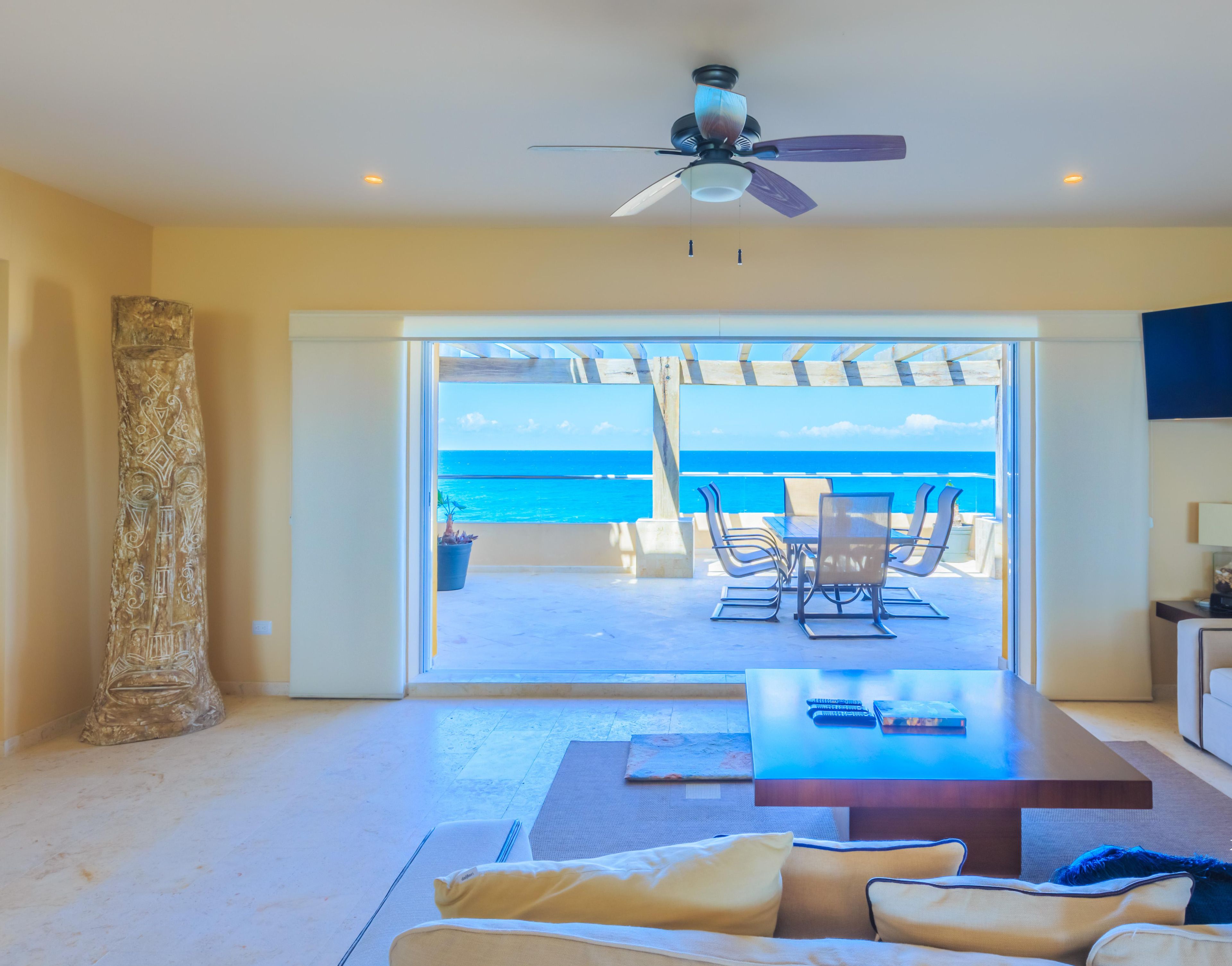 A spacious living area with a large sliding glass door leading to a balcony overlooking the ocean.