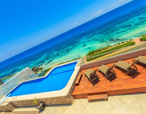 A pool with a wooden deck and lounge chairs overlooking the ocean. - Luxury. 4 BR PH Ocean View + Private Pool (Isla Mujeres)