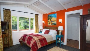 Un dormitorio con cama, televisión, un cuadro y una puerta.