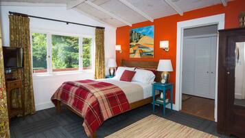 A bedroom with a bed, a television, a painting, and a door.
