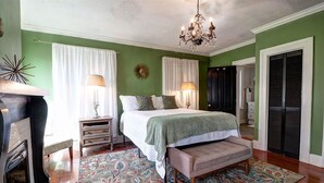A bedroom with a bed, bedside lamps, a chandelier, a fireplace, and a patterned rug. - Jones Green Room Loft Apartment -Dog Friendly Upon Approval! (Savannah)