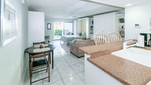 A modern kitchen with a granite countertop, a dining area with a table and chairs, and a living area with a sofa and a coffee table.