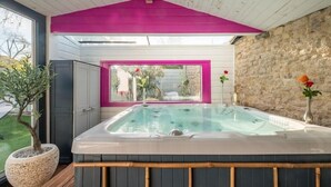 Un bain à remous avec vue sur un jardin et un mur en pierre.