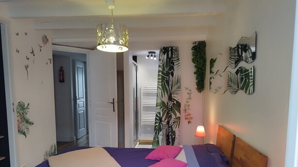 Une chambre à coucher avec un lit, des oreillers, une lampe de chevet et une porte donnant sur une autre pièce.