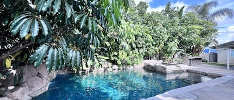 En swimmingpool omgiven av frodig grönska och stenkonstruktioner.