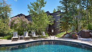 A swimming pool with lounge chairs and a building in the background. - Mountain-Chic Chalet | Aspenwood #KA | 2B/2B (Snowmass Village)
