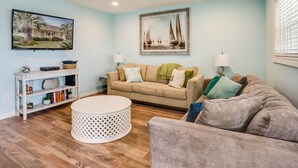 Ein Wohnzimmer mit einem beigen Sofa, einem runden Couchtisch und einem Deckenventilator.