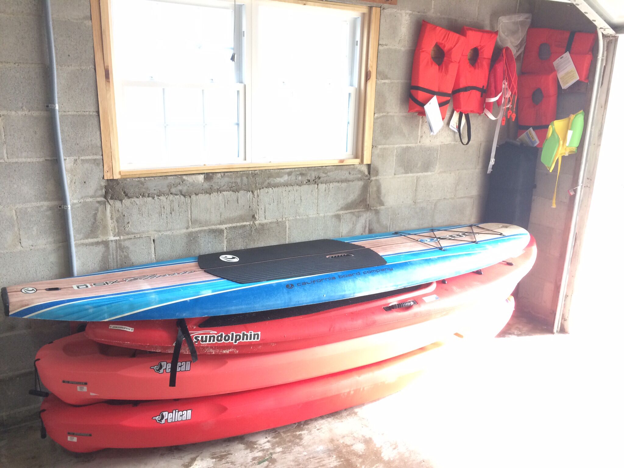 Ein Lagerraum mit Kajaks und Schwimmwesten an einer Wand.