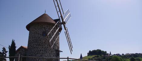Un moulin à vent en pierre, avec une clôture en bois au premier plan.