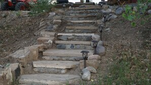 A set of stone steps leading up a hill, surrounded by rocks and vegetation.