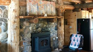 A cozy cabin interior with a stone fireplace, wooden beams, and a rustic aesthetic.