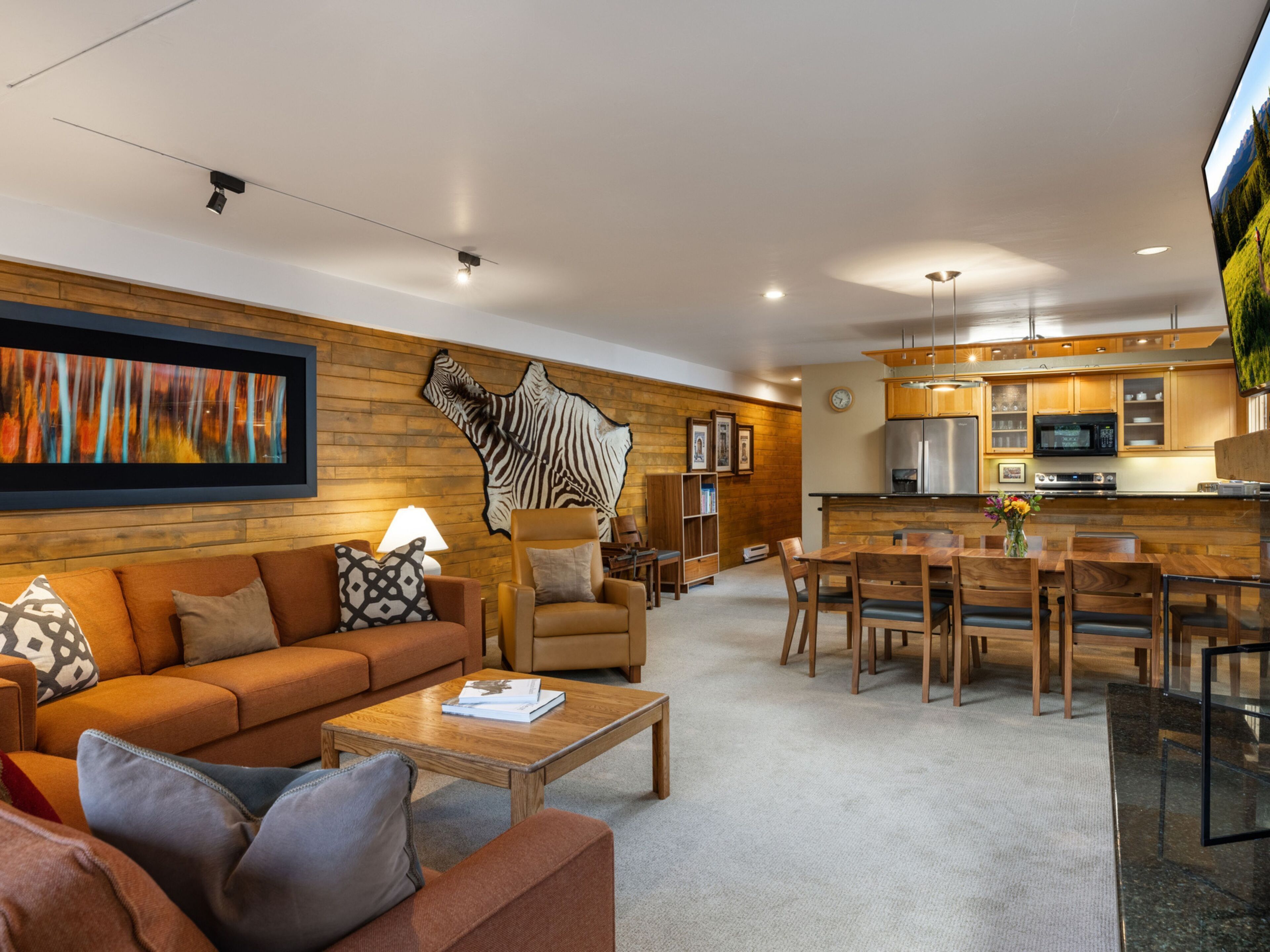 A modern living room with a sofa, coffee table, and a dining area with wooden chairs and a table.