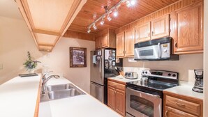 A modern kitchen with wooden cabinets, stainless steel appliances, and a white countertop. - 3/2 Ski In/Out  BEAVER CREEK, steps to Village, Townsend Place A307 (Beaver Creek)