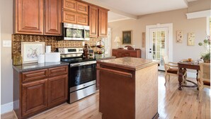 A kitchen with wooden cabinets, stainless steel appliances, and a marble countertop. - "Historical”Yellow TeaCup Cottage,Farm setting, horses &goats ,rest n relax  (Rockford)