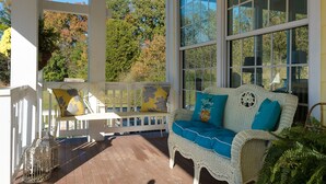 A covered porch with a wicker sofa, a bench, and a birdcage. - "Historical”Yellow TeaCup Cottage,Farm setting, horses &goats ,rest n relax  (Rockford)