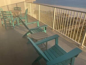 Relax on the balcony with a view of the beach, surrounded by comfortable seating and a small table.