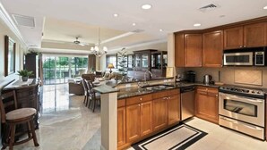 A spacious kitchen with wooden cabinets, a large island, stainless steel appliances, and a dining area with a view.