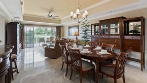 A dining area with a large wooden table, chairs, a chandelier, and a view of the outdoors.