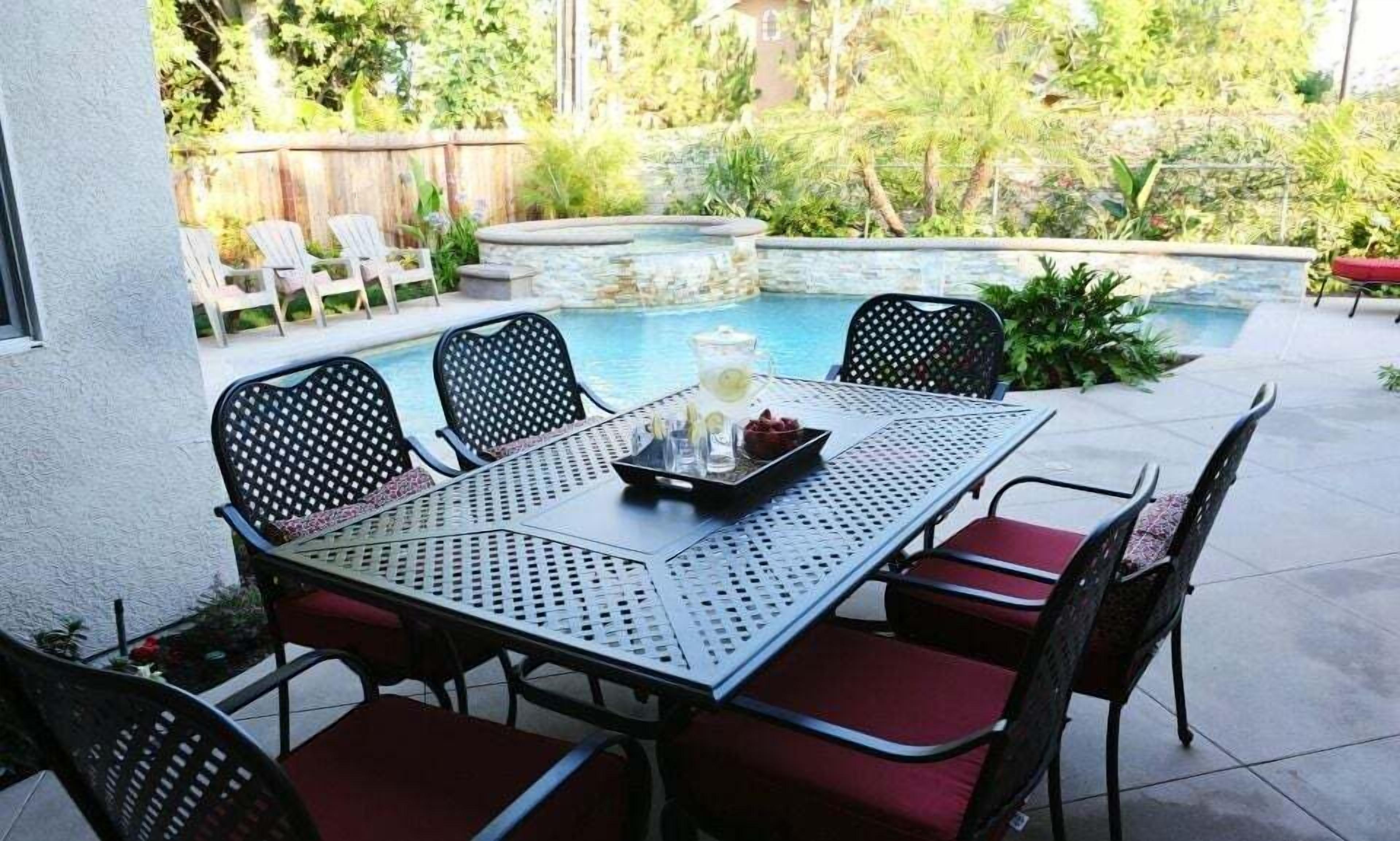 A patio with a pool table, chairs, and a small table with drinks and snacks.