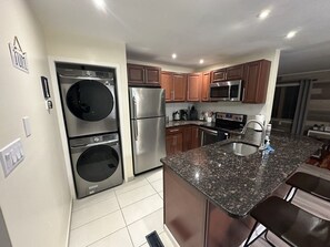 Una cocina moderna con electrodomésticos de acero inoxidable, armarios de madera y encimera de granito.