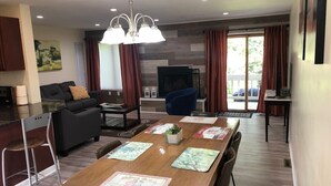 A modern living room with a dining table, sofa, and TV. - Whitetail Retreat-Hiking, Biking & River adventure (East Stroudsburg)